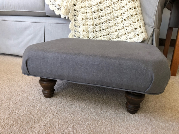 Alisa, Interior design category: A comfy, roomy footstool covered with the IL019 in Asphalt.