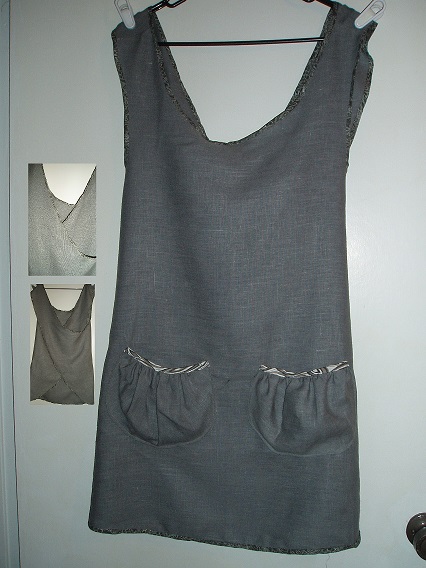 Cynthia, A gray linen criss-cross tunic apron, trimmed with contrasting gray and white bias tape and two gath...