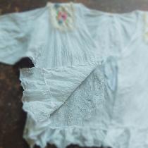 A light cover up in white linen with crushed ruffles, vintage doily and tie front.